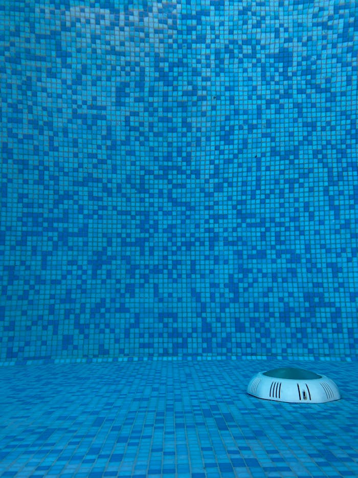 Vibrant blue mosaic tiles in a swimming pool with a visible drain.